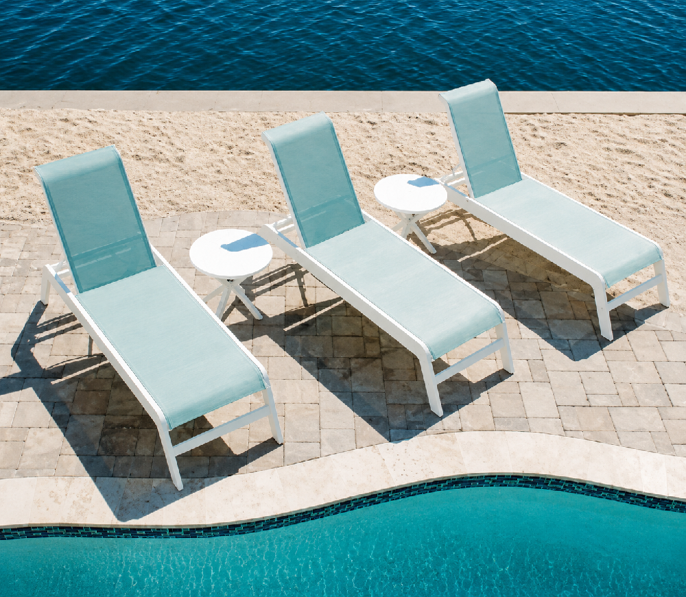 Modern sling chaise lounges with aqua colored fabric positioned beside a commercial pool for upscale resort seating.